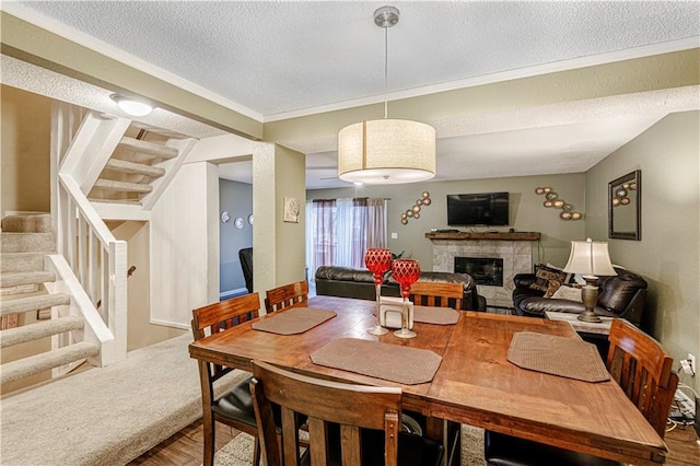 5933 Ridgeway Ave, Kansas City, MO 64133 - dining room with a glass covered fireplace, wood finished floors, stairs, crown molding, and a textured ceiling