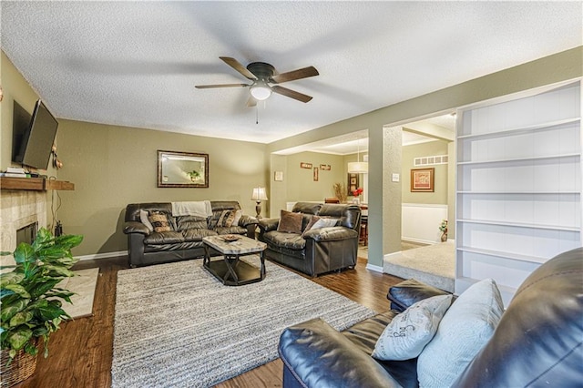 5933 Ridgeway Ave, Kansas City, MO 64133 - living room with a textured ceiling, wood finished floors, visible vents, a ceiling fan, and a tiled fireplace