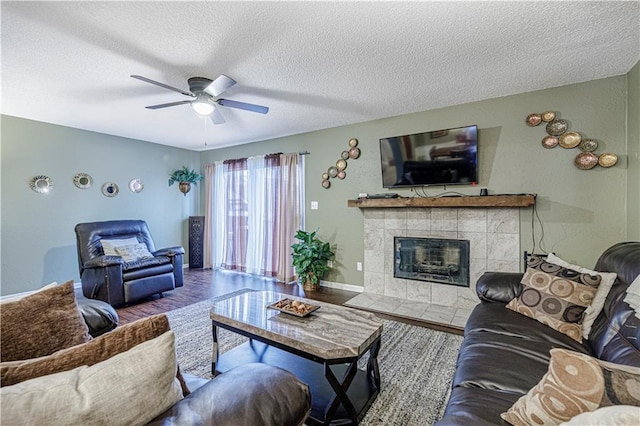 5933 Ridgeway Ave, Kansas City, MO 64133 - living area with baseboards, a ceiling fan, a tile fireplace, wood finished floors, and a textured ceiling