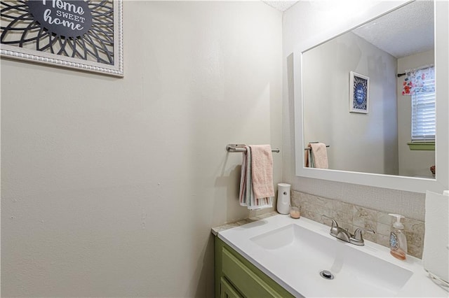 5933 Ridgeway Ave, Kansas City, MO 64133 - bathroom with a textured ceiling, backsplash, and vanity