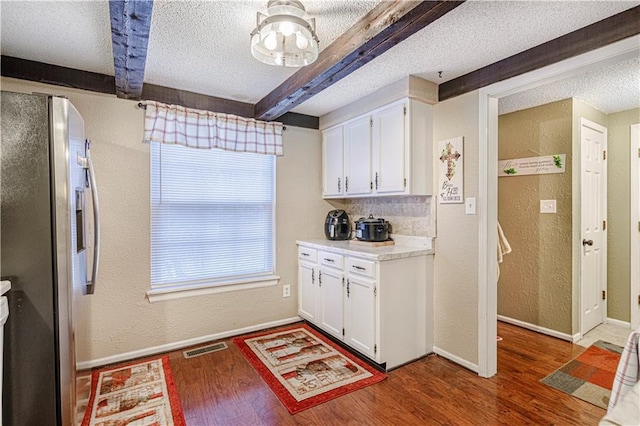 5933 Ridgeway Ave, Kansas City, MO 64133 - kitchen with beam ceiling, freestanding refrigerator, white cabinetry, a textured ceiling, and wood finished floors