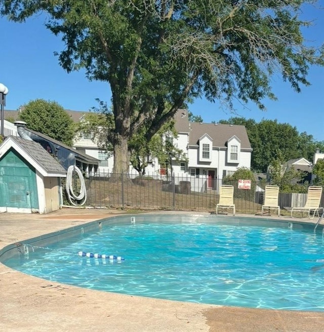 5933 Ridgeway Ave, Kansas City, MO 64133 - community pool featuring a storage shed, fence, and an outbuilding