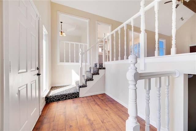 foyer entrance featuring lofted ceiling, stairs, baseboards, and wood finished floors