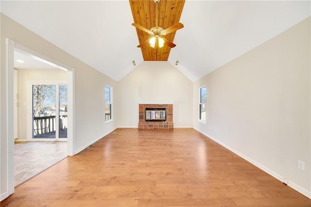 unfurnished living room with light wood-type flooring, plenty of natural light, a fireplace, and a ceiling fan