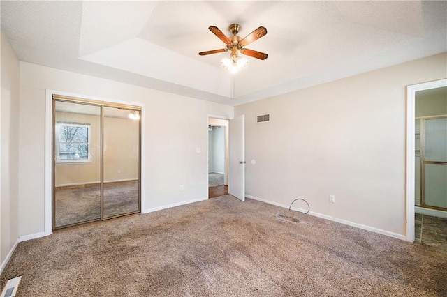 unfurnished bedroom with baseboards, visible vents, a raised ceiling, and carpet floors