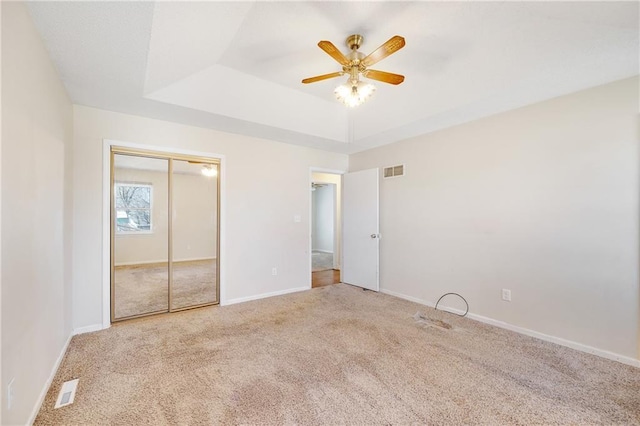 unfurnished bedroom featuring visible vents, carpet flooring, baseboards, and a tray ceiling