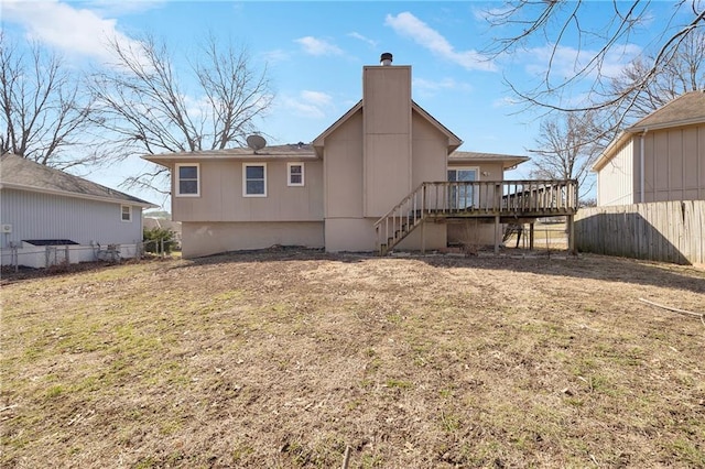 rear view of property featuring a chimney, stairs, a deck, and fence