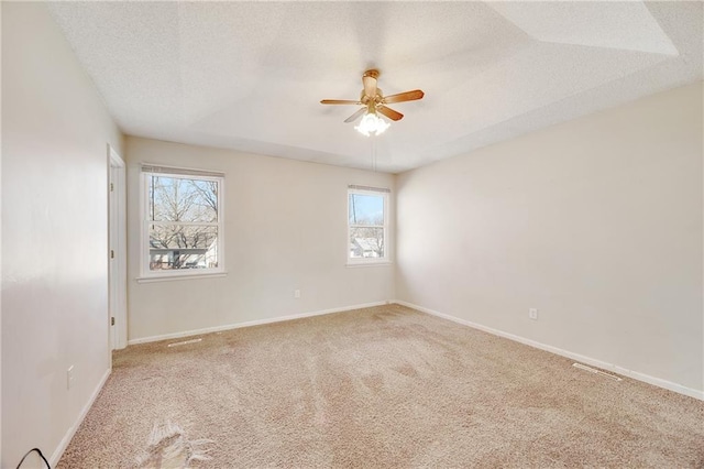 carpeted spare room with baseboards, a raised ceiling, a textured ceiling, and ceiling fan