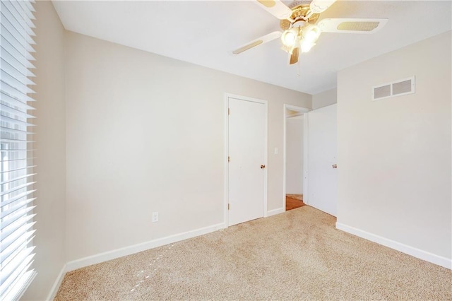 carpeted empty room with visible vents, baseboards, and a ceiling fan