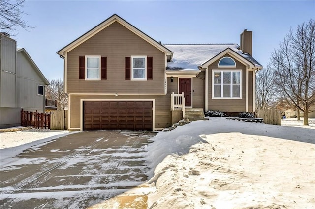 view of front of home with an attached garage, a chimney, and fence