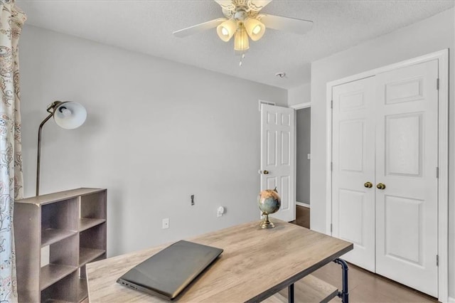 home office featuring a ceiling fan, a textured ceiling, and wood finished floors