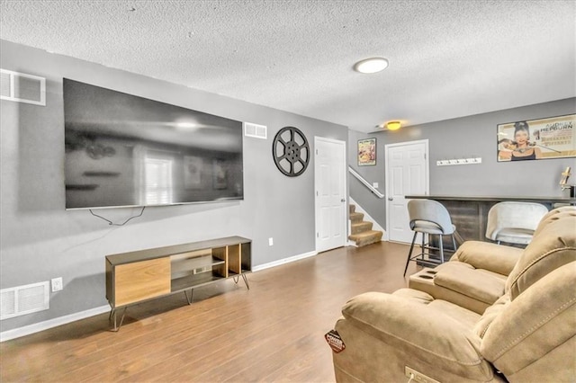 living room featuring stairway, visible vents, and wood finished floors