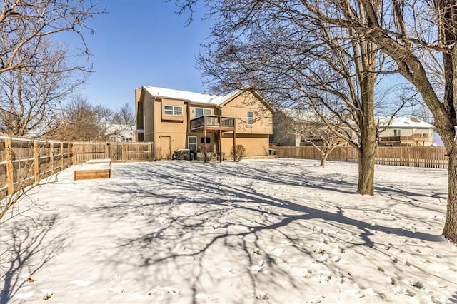 snow covered property featuring a fenced backyard and stucco siding