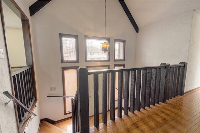 staircase with beamed ceiling, high vaulted ceiling, and hardwood / wood-style floors