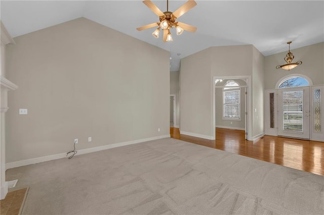 interior space featuring baseboards, high vaulted ceiling, carpet floors, and ceiling fan