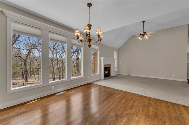 unfurnished living room with lofted ceiling, wood finished floors, baseboards, and a wealth of natural light