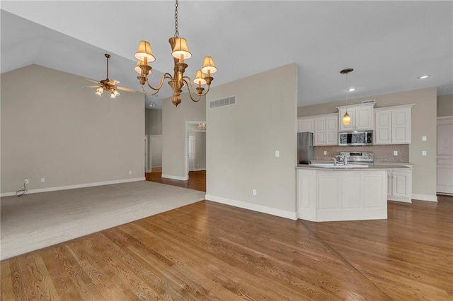 kitchen featuring visible vents, ceiling fan with notable chandelier, open floor plan, stainless steel appliances, and decorative backsplash