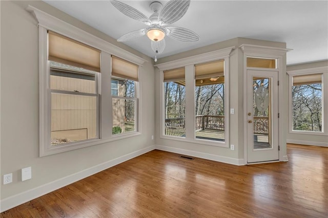 unfurnished sunroom featuring visible vents, a healthy amount of sunlight, and ceiling fan