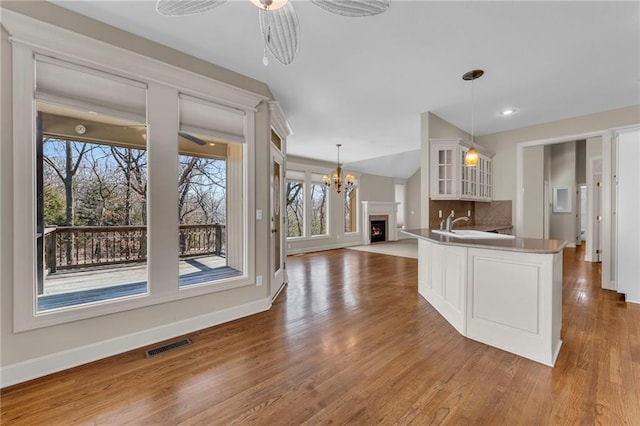 kitchen featuring white cabinetry, decorative light fixtures, glass insert cabinets, and open floor plan