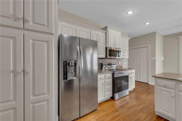 kitchen featuring backsplash, appliances with stainless steel finishes, and white cabinets