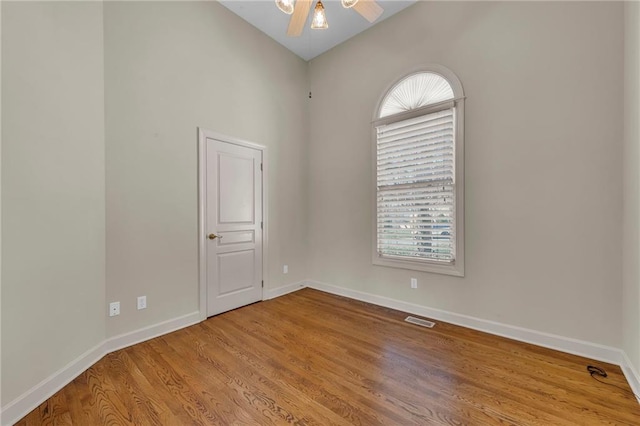 empty room featuring baseboards, wood finished floors, visible vents, and ceiling fan