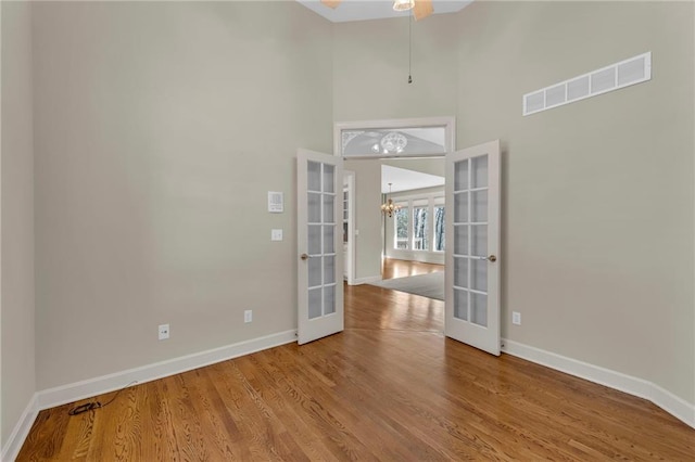 empty room featuring wood finished floors, french doors, visible vents, and baseboards