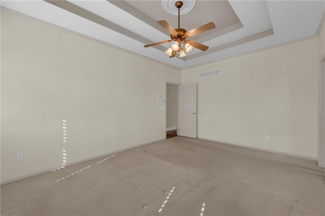 carpeted spare room featuring visible vents, a raised ceiling, baseboards, and a ceiling fan