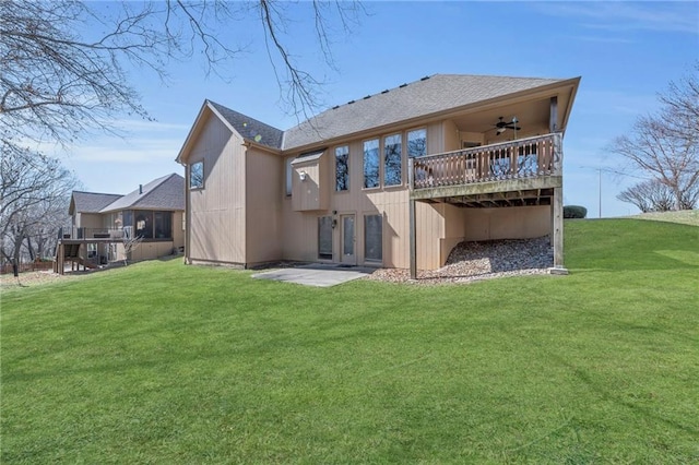 back of property with a lawn, a wooden deck, a ceiling fan, and a shingled roof