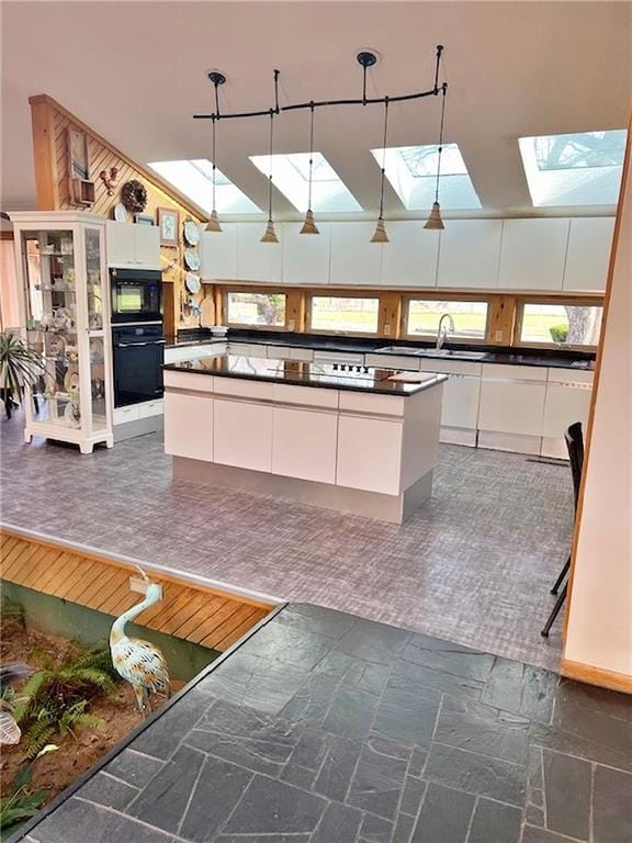 kitchen with white cabinetry, dark countertops, a skylight, and black microwave