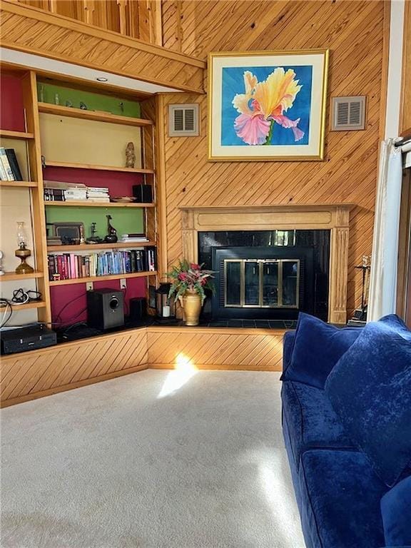living area with visible vents, wood walls, and a glass covered fireplace
