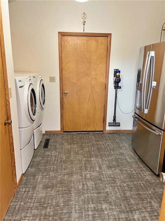 clothes washing area with washer and clothes dryer, baseboards, dark colored carpet, and laundry area