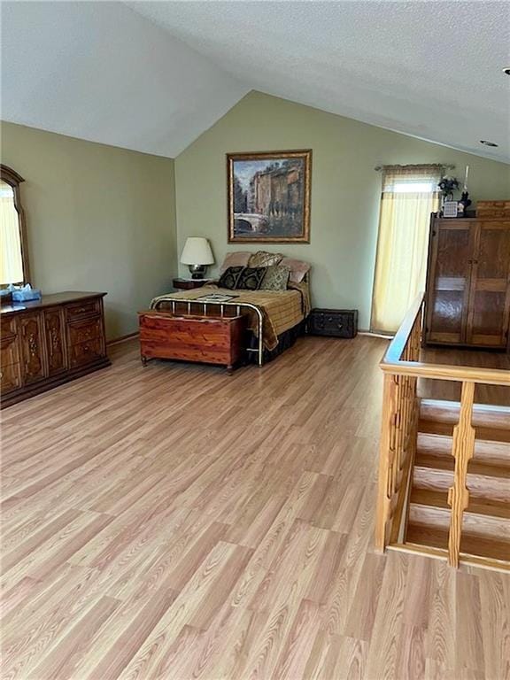 bedroom featuring lofted ceiling, a textured ceiling, and light wood-style flooring