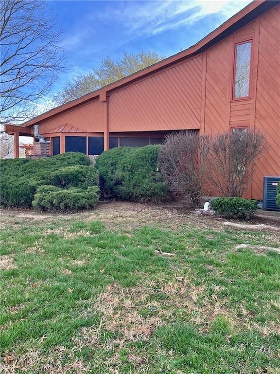 view of side of home with central AC and a yard