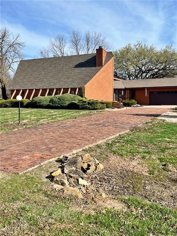 view of property exterior with a chimney, driveway, and an attached garage