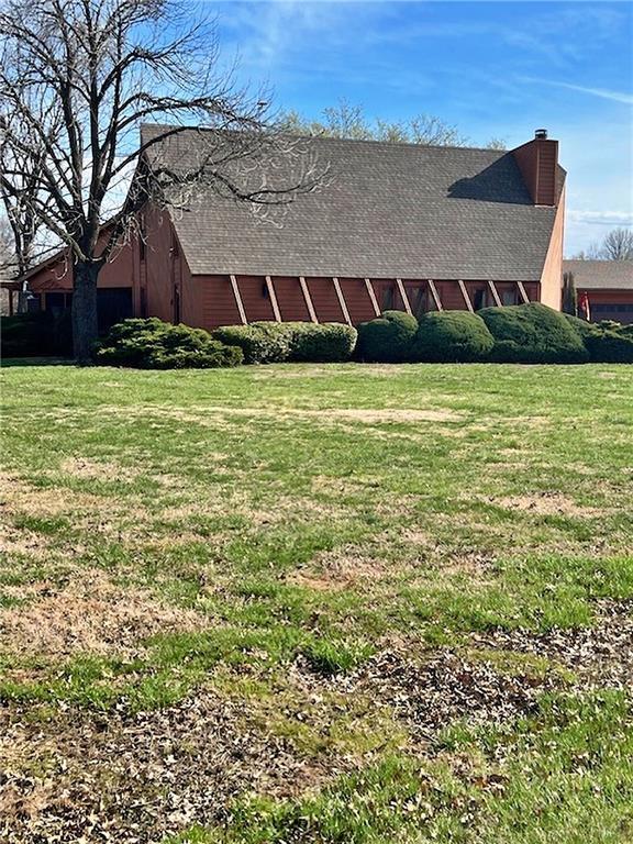 view of property exterior with a lawn, a chimney, and a barn