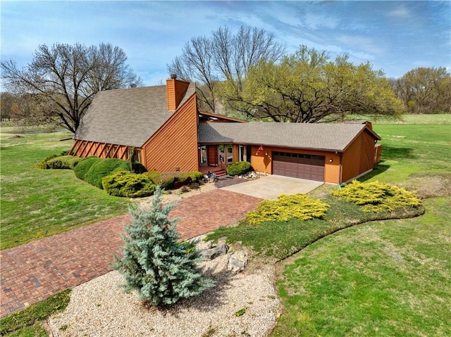 view of front of home with a chimney, a garage, concrete driveway, a front lawn, and roof with shingles