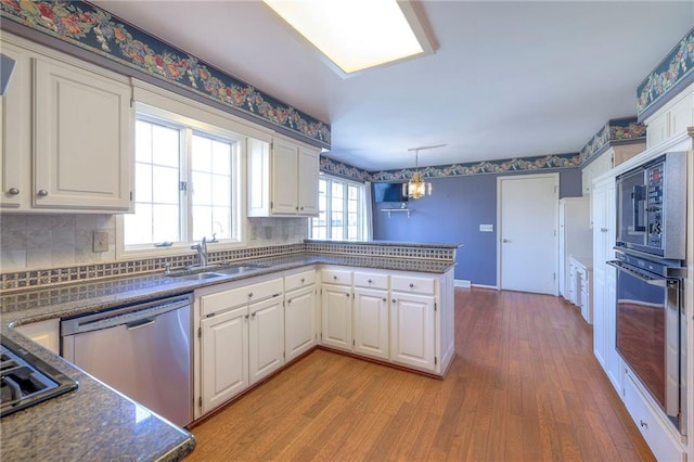 kitchen featuring a sink, white cabinets, a peninsula, and stainless steel dishwasher