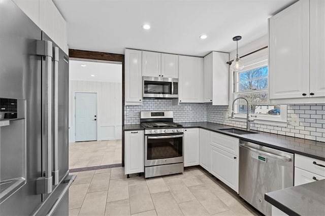 kitchen with stainless steel appliances, dark countertops, a sink, and decorative backsplash