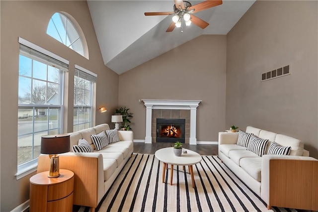 living room with plenty of natural light, visible vents, wood finished floors, and a tile fireplace