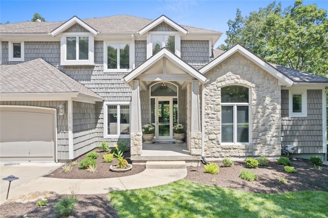 view of front facade with stone siding, roof with shingles, and an attached garage