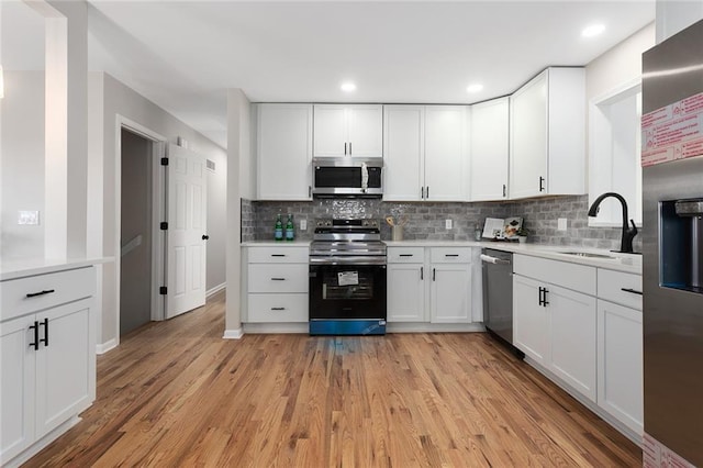 kitchen with light wood-type flooring, appliances with stainless steel finishes, light countertops, and a sink