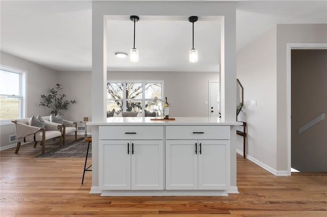 kitchen featuring decorative light fixtures, white cabinets, and light wood-style flooring