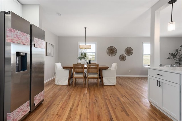 dining space with a wealth of natural light, light wood-style flooring, and baseboards