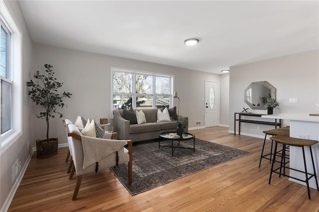 living area with wood finished floors, visible vents, and baseboards