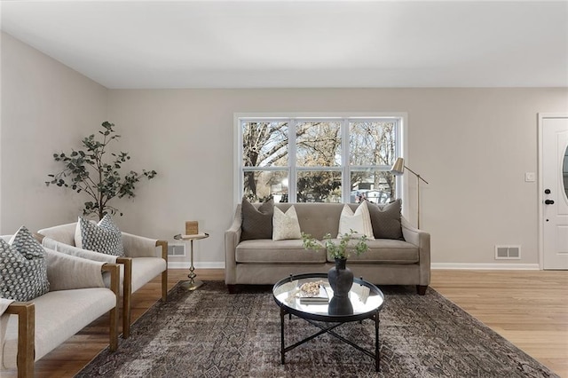 living area featuring wood finished floors, visible vents, and baseboards