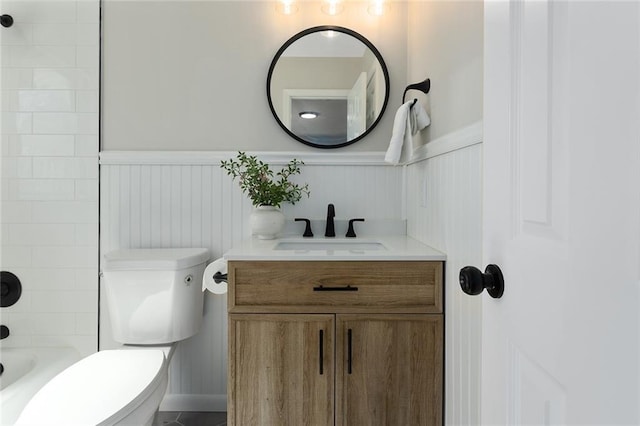 bathroom featuring wainscoting, shower / bathing tub combination, vanity, and toilet