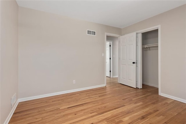 unfurnished bedroom with light wood-style floors, baseboards, visible vents, and a closet