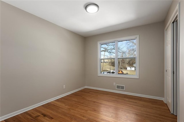 unfurnished bedroom with wood finished floors, visible vents, and baseboards