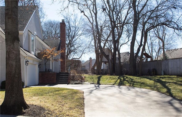 view of yard with an attached garage, fence, and concrete driveway