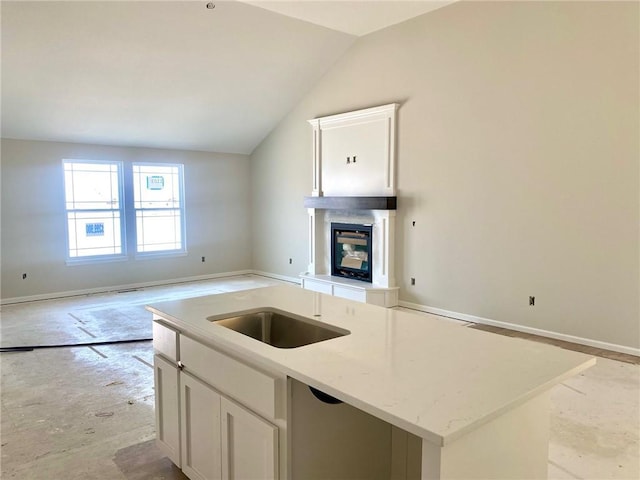 1103 Noah Ln, Kearney, MO 64060 - kitchen featuring a glass covered fireplace, a center island with sink, vaulted ceiling, open floor plan, and white cabinetry